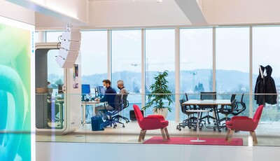 Interior of an modern smart glass building with large windows and a men working at their desks.