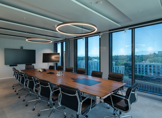 Interior of the building, a desk in the middle of the space. Background: SageGlass tinted.