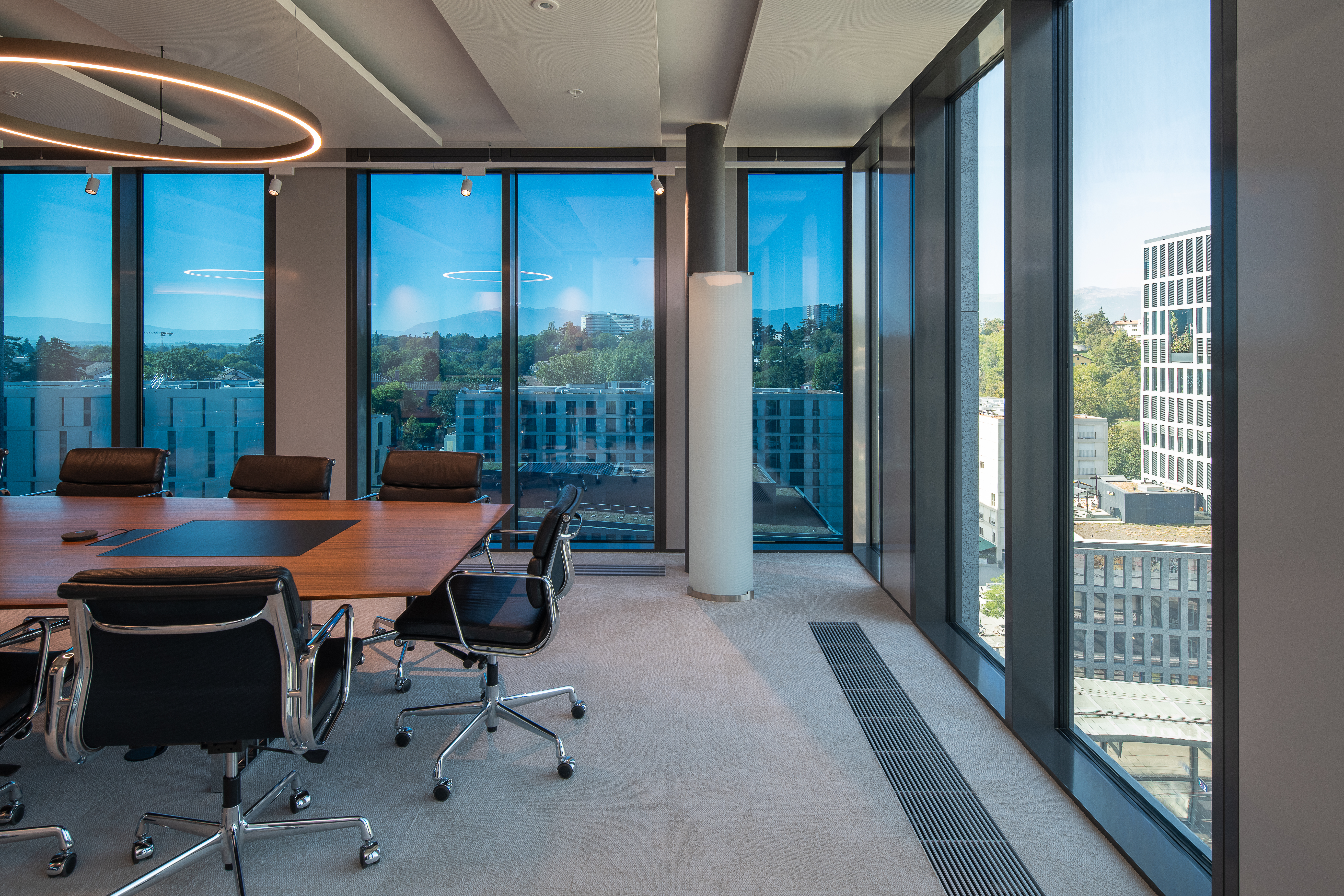 Workspace in Alto Pont-Rouge building. There is a table and chairs. The space is equipped with SageGlass smart windows, which is tinted.